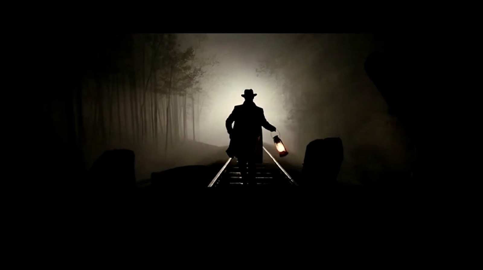 a man walking down a train track in the dark