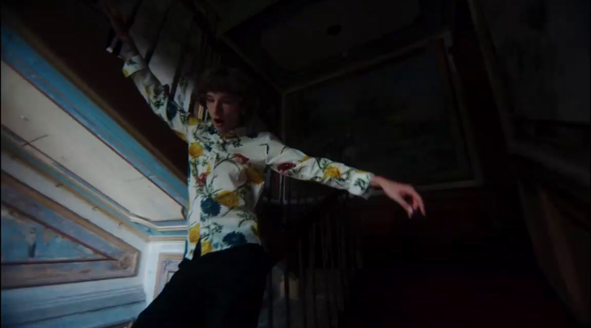 a man in a floral shirt standing on a stair case