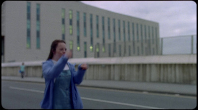 a woman standing on the side of a road holding a cell phone