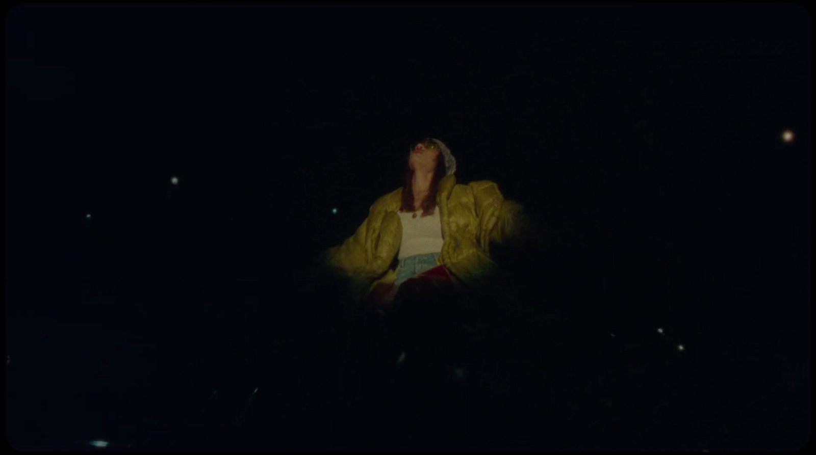 a person standing in the dark with a yellow jacket