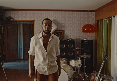 a man standing in a living room next to a drum set