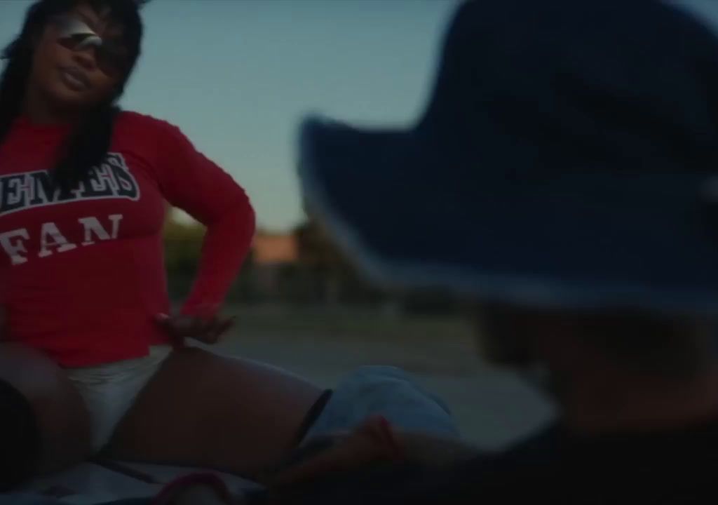 a woman in a red shirt is sitting on a beach