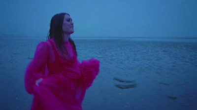 a woman in a pink dress standing on a beach