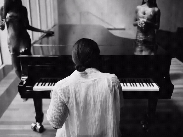 a woman sitting at a piano in front of a mirror