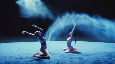 a couple of women sitting on top of a blue surface