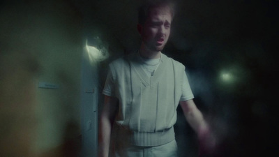 a man standing in a dark room with his hands in his pockets