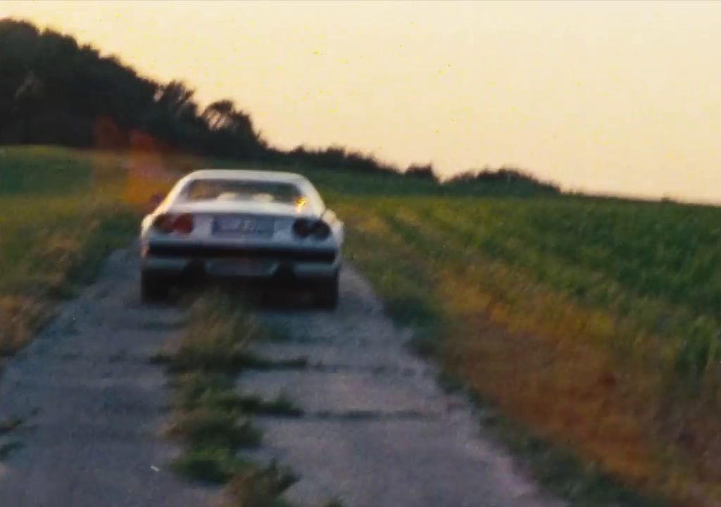 a car parked on a dirt road near a field