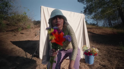 a woman kneeling down holding a bunch of flowers