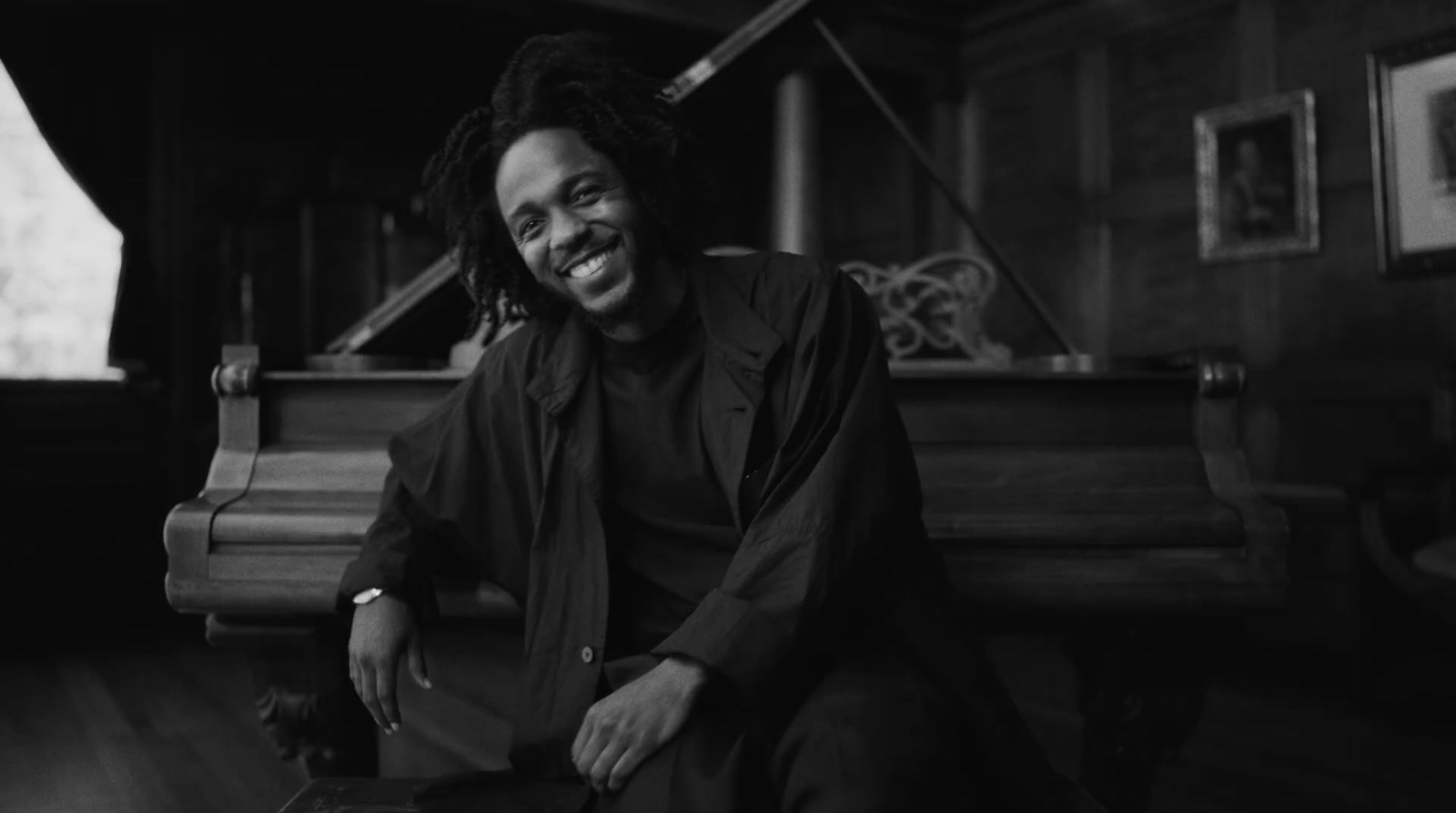 a man with dreadlocks sitting in front of a piano