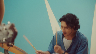 a man playing drums in front of a blue wall