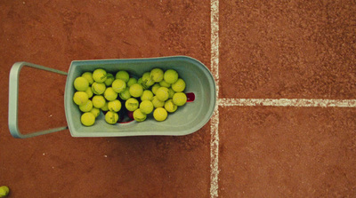 a bucket full of tennis balls on a tennis court