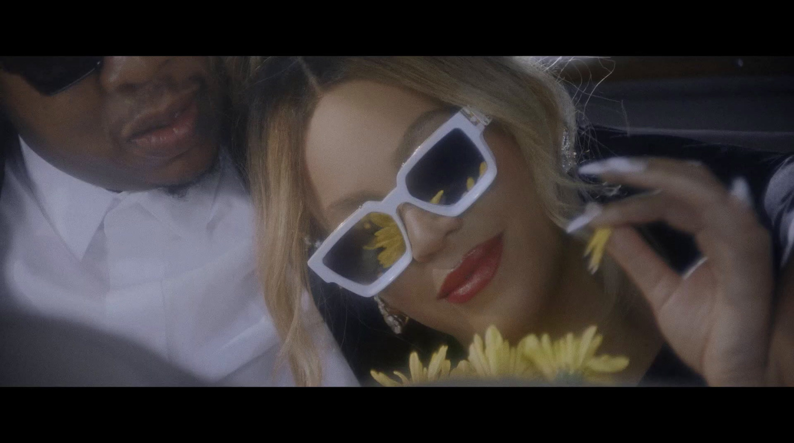 a woman in sunglasses and a man in a tuxedo