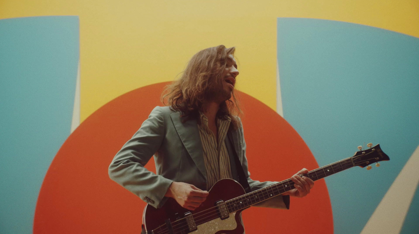 a man with long hair playing a guitar