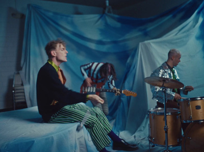 a man sitting on top of a bed next to a drum set