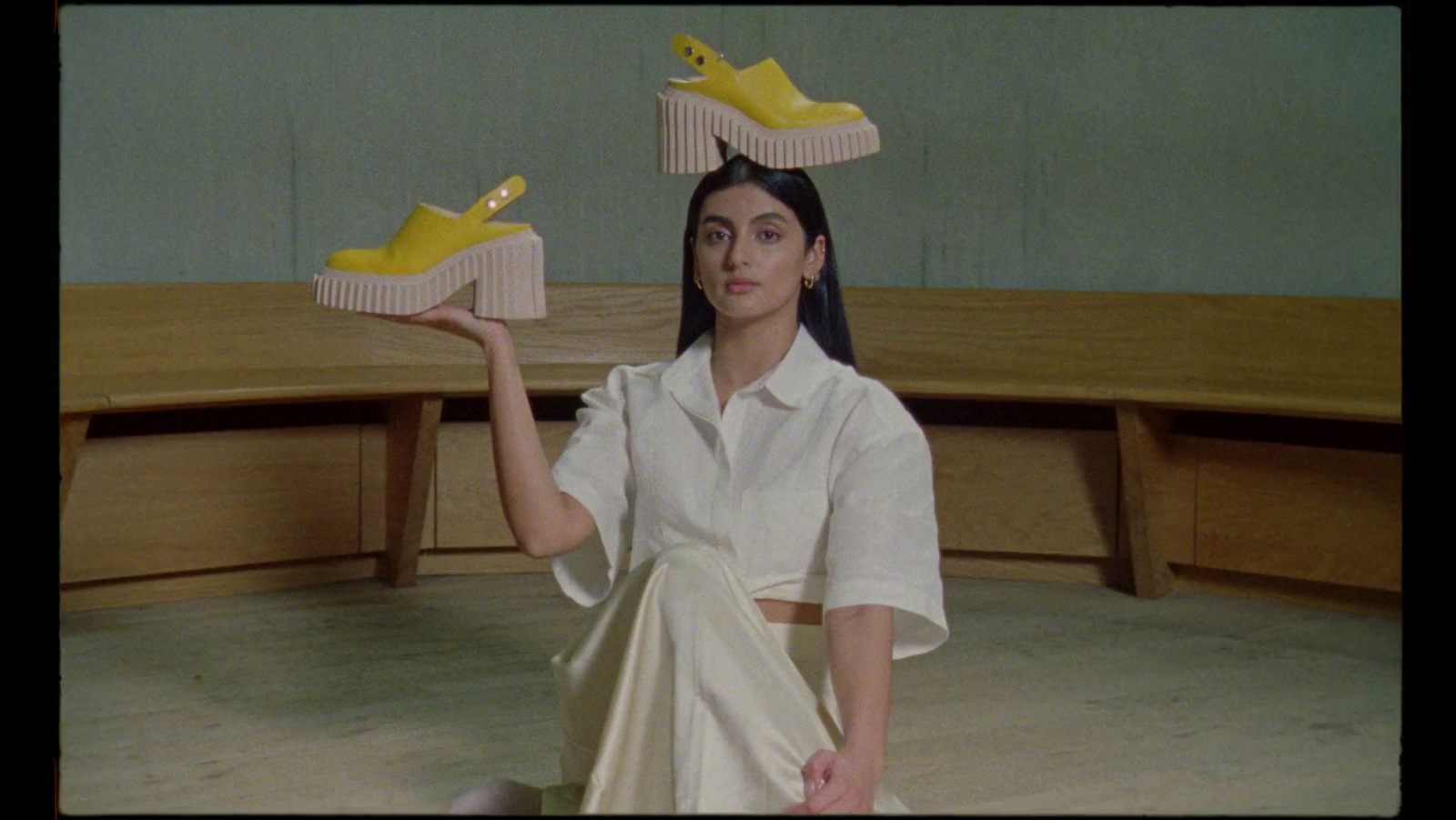 a woman sitting on the floor with yellow shoes on her head