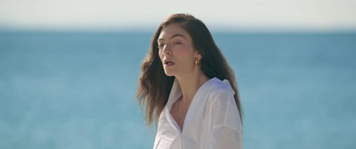 a woman with long hair standing in front of the ocean