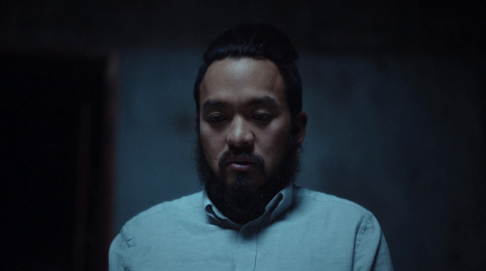 a man with a beard standing in a dark room