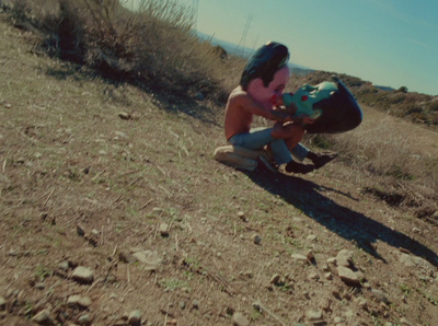 a woman kneeling down on top of a dirt field