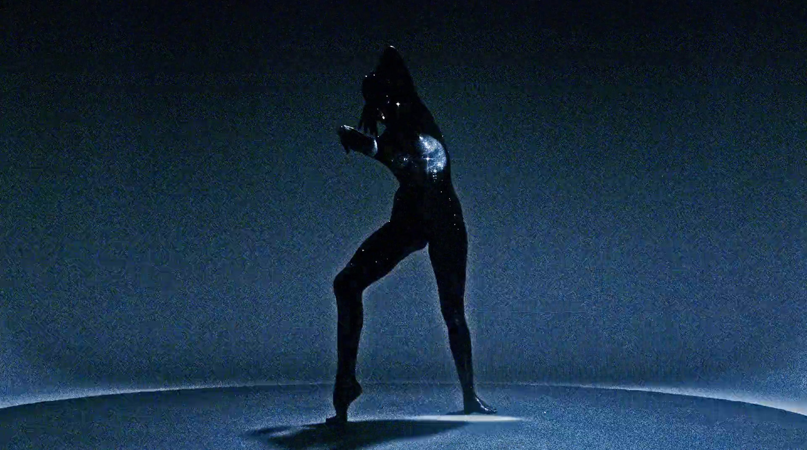 a woman in a black bodysuit standing in the dark