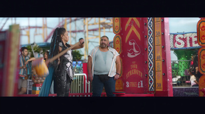 a man and a woman standing in front of a carnival ride