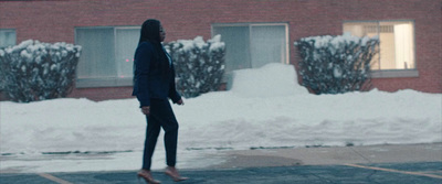 a woman walking across a parking lot in front of a building