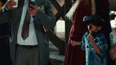 a man standing next to a little boy holding a smart phone