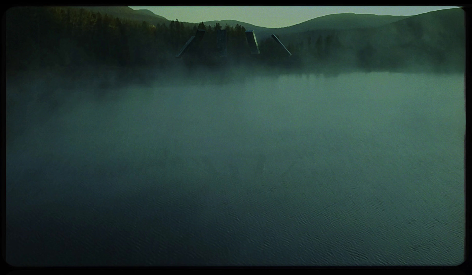 a foggy lake with trees in the distance