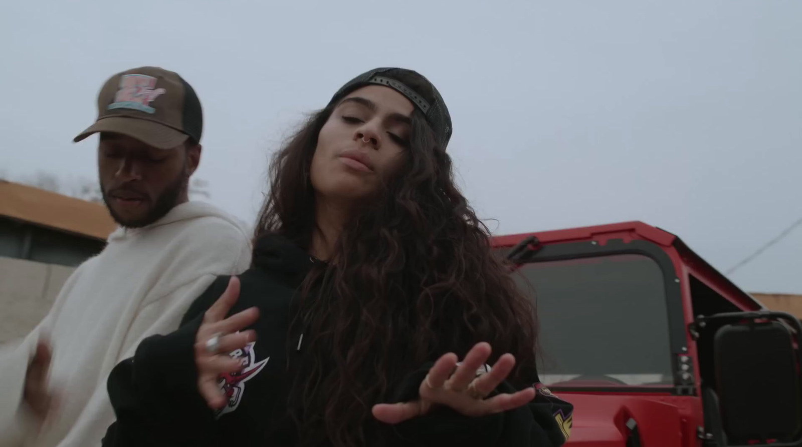 a man and a woman standing in front of a red truck