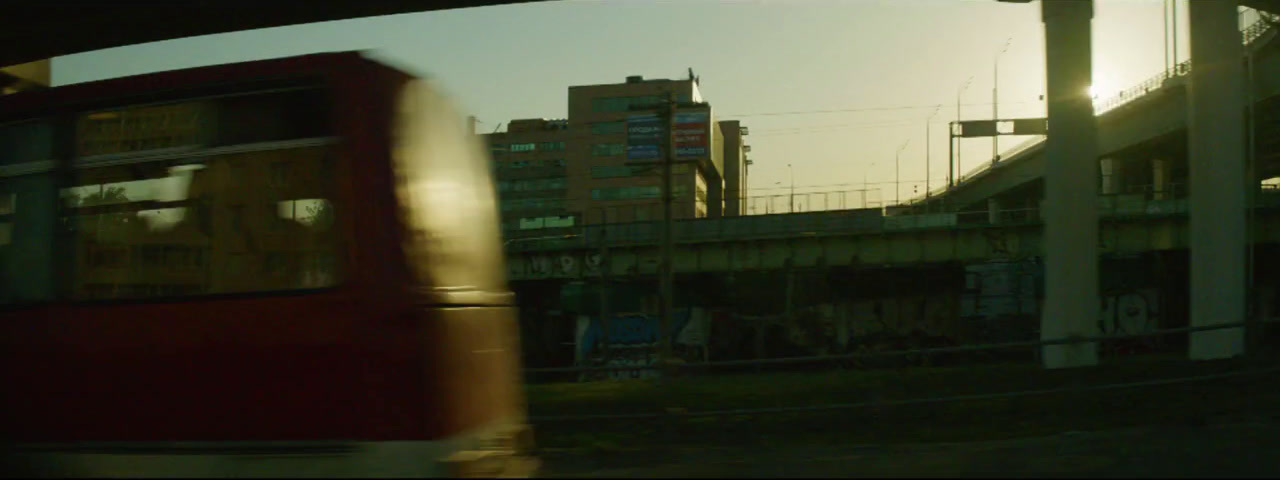 a red train traveling past a tall building