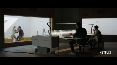 a man and woman sitting at a desk in front of a tv