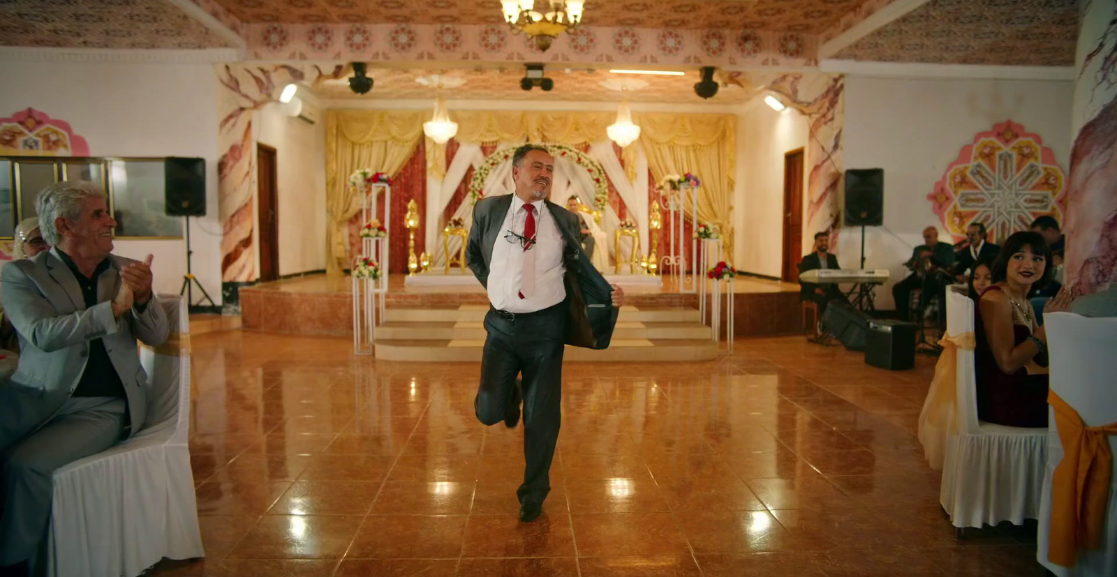 a man in a suit and tie walking through a hall