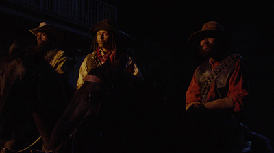 three men sitting on horses in the dark