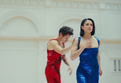 a woman in a red and blue dress standing next to a man in a red