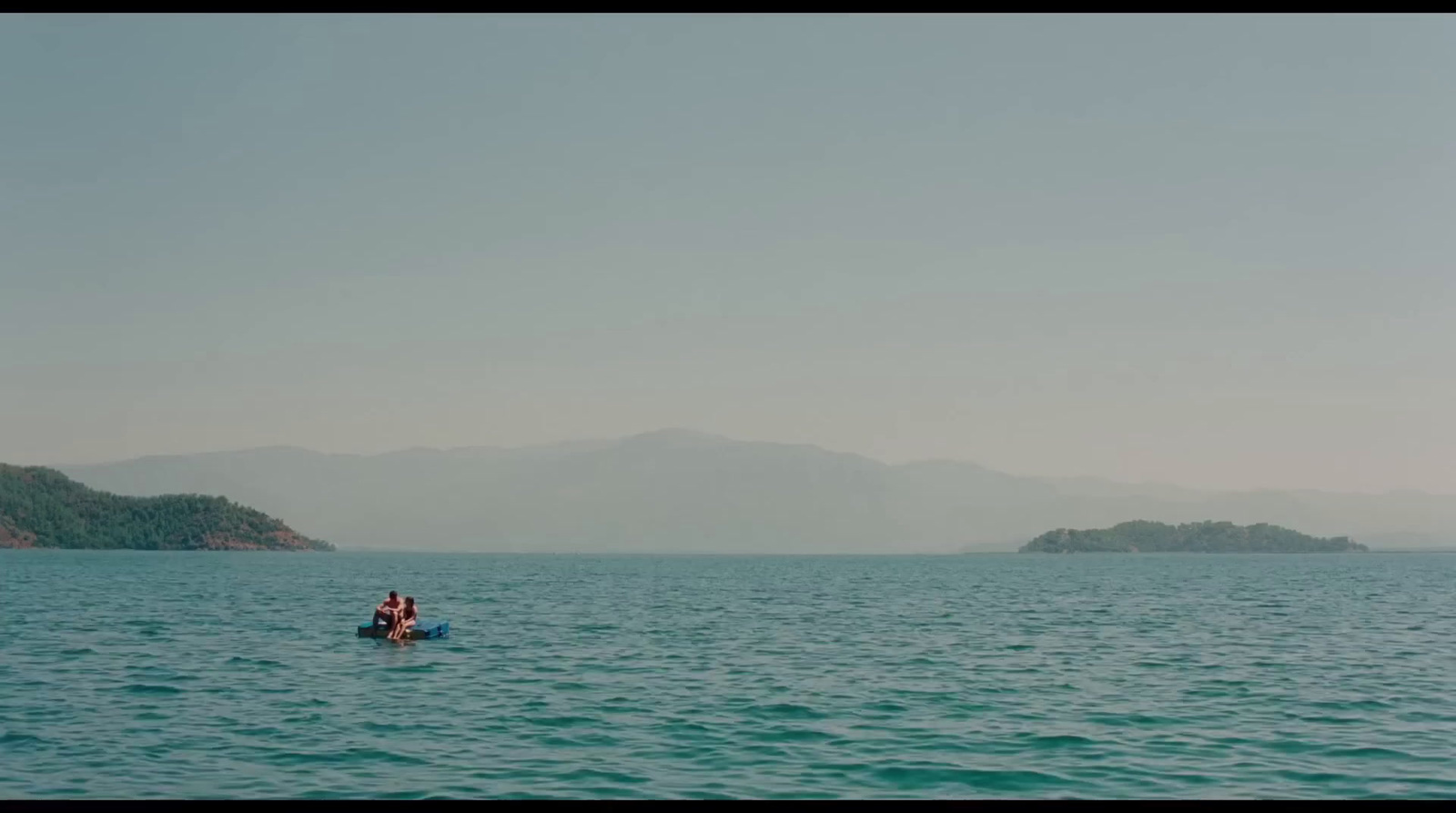 two people in a small boat in the middle of the ocean