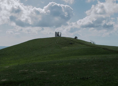 a grassy hill with a house on top of it