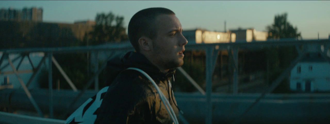 a man standing in front of a bridge at dusk