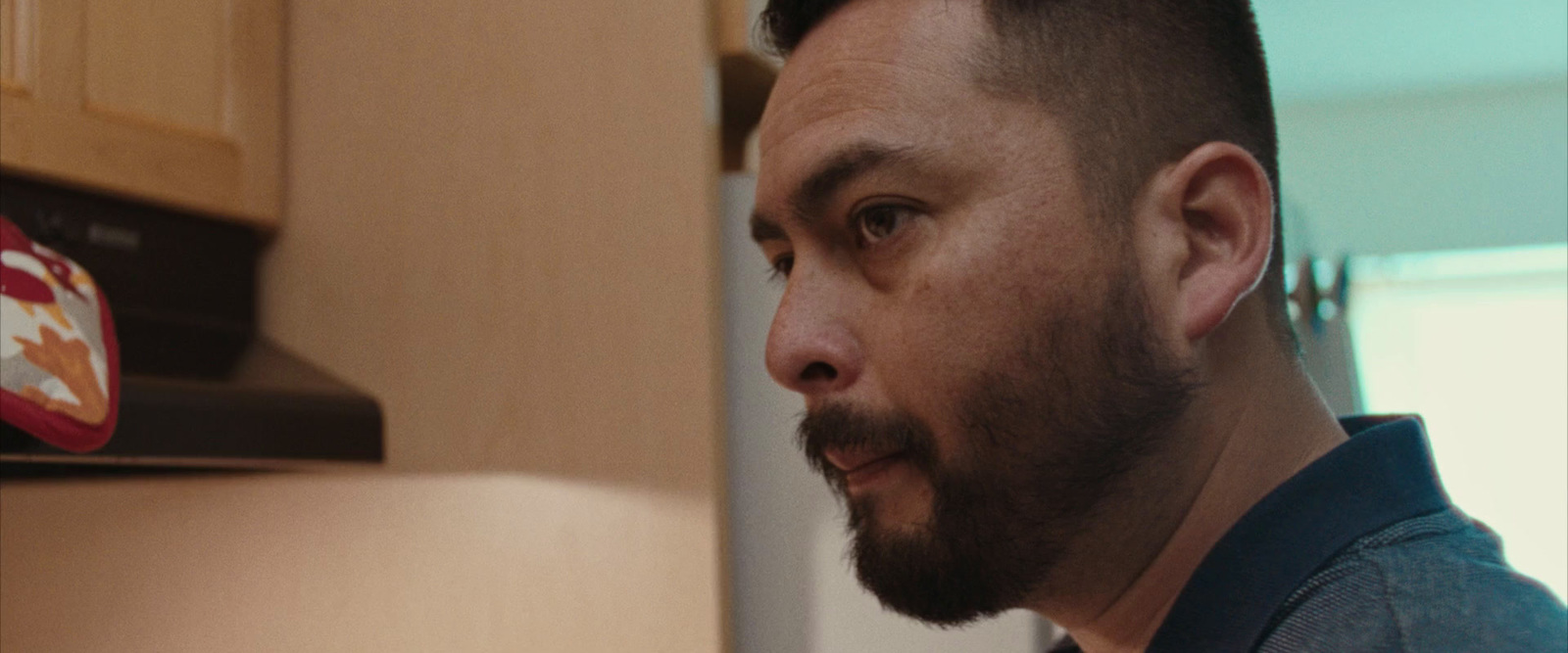 a man with a beard standing in a kitchen