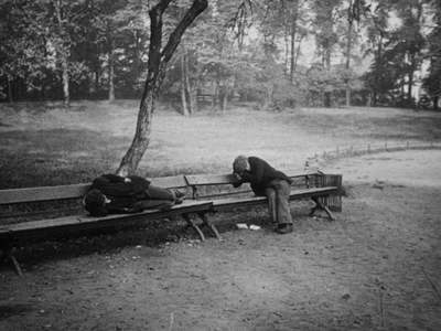 a black and white photo of a man sitting on a park bench