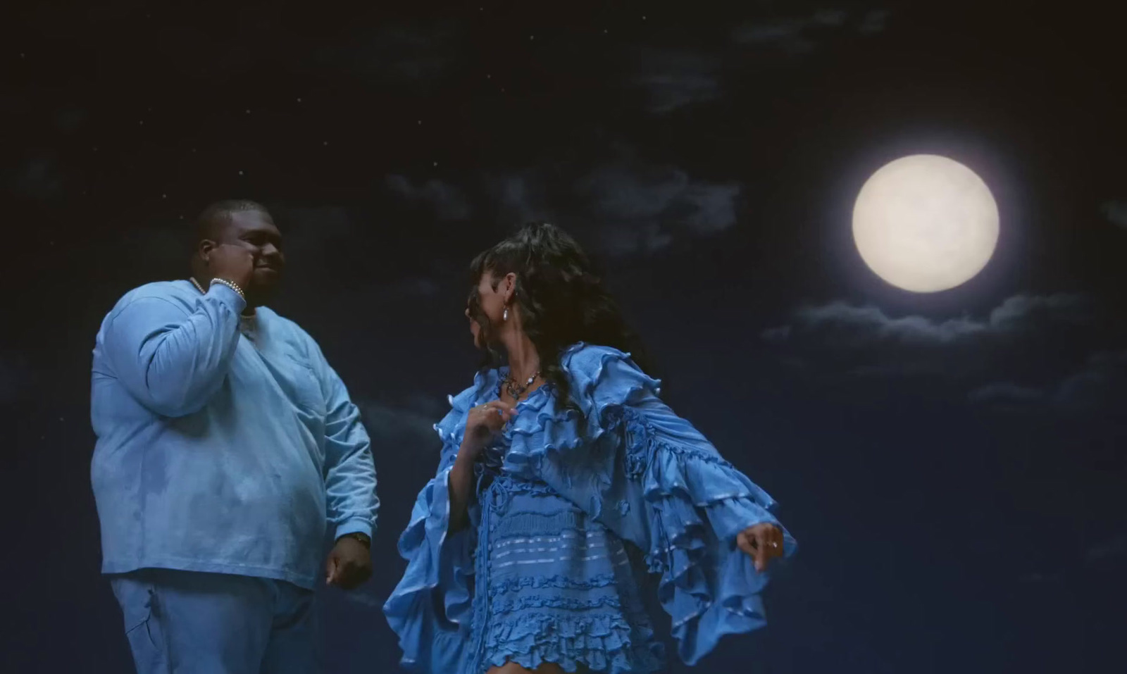 a man and a woman standing in front of a full moon