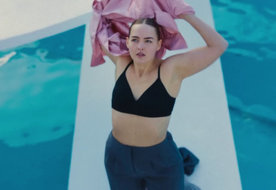 a woman in a black bikini top holding a pink scarf over her head