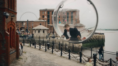 a person in a hamster on a sidewalk near a body of water