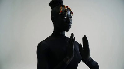 a woman in a black bodysuit with beads on her head