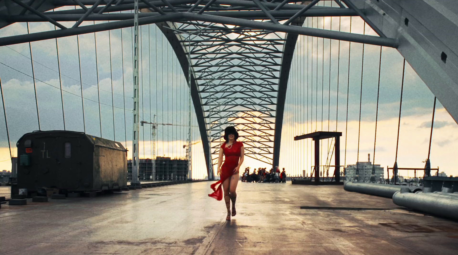 a woman in a red dress walking across a bridge