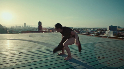 a woman bending over on a roof with a city in the background