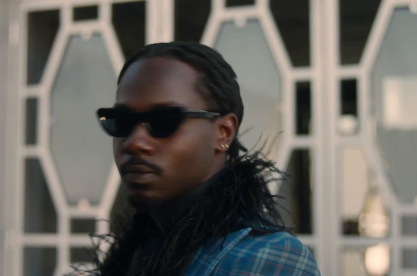 a man with long hair and sunglasses standing in front of a building