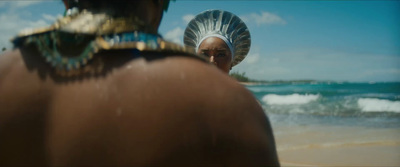 a woman in a headdress standing on the beach