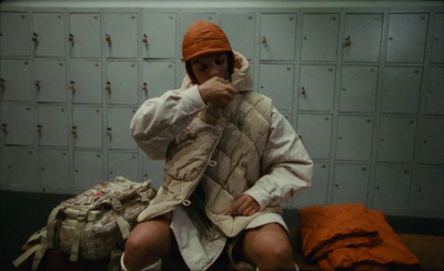 a person sitting on a bed in a locker room