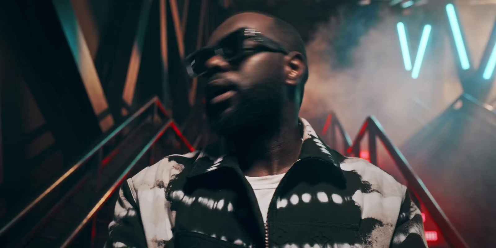 a man with a beard and glasses standing in front of a stage