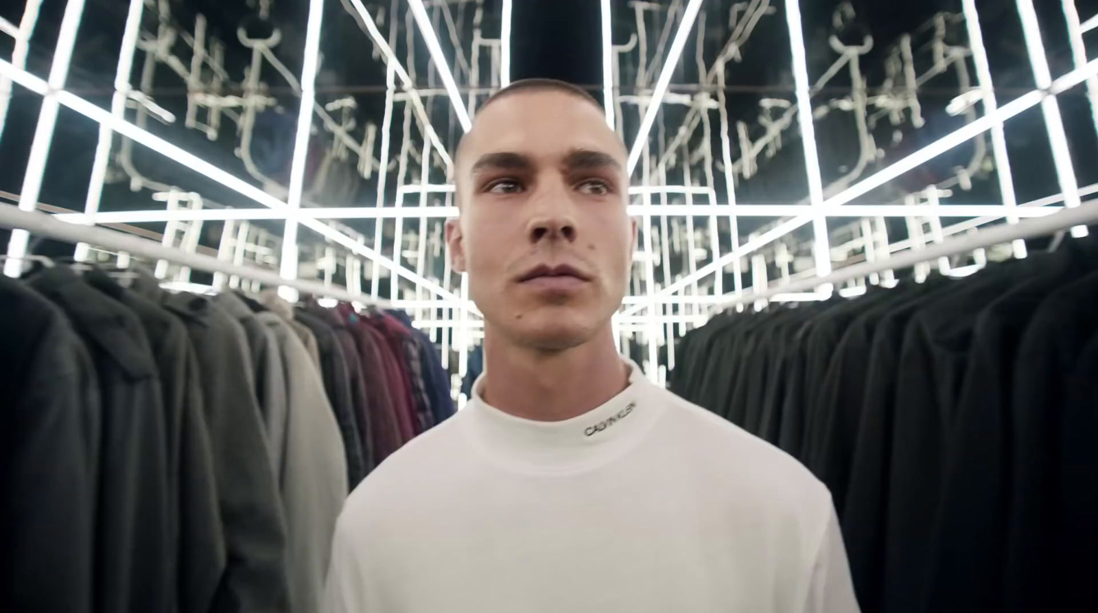 a man standing in front of a rack of shirts