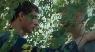 a man standing under a tree next to a forest